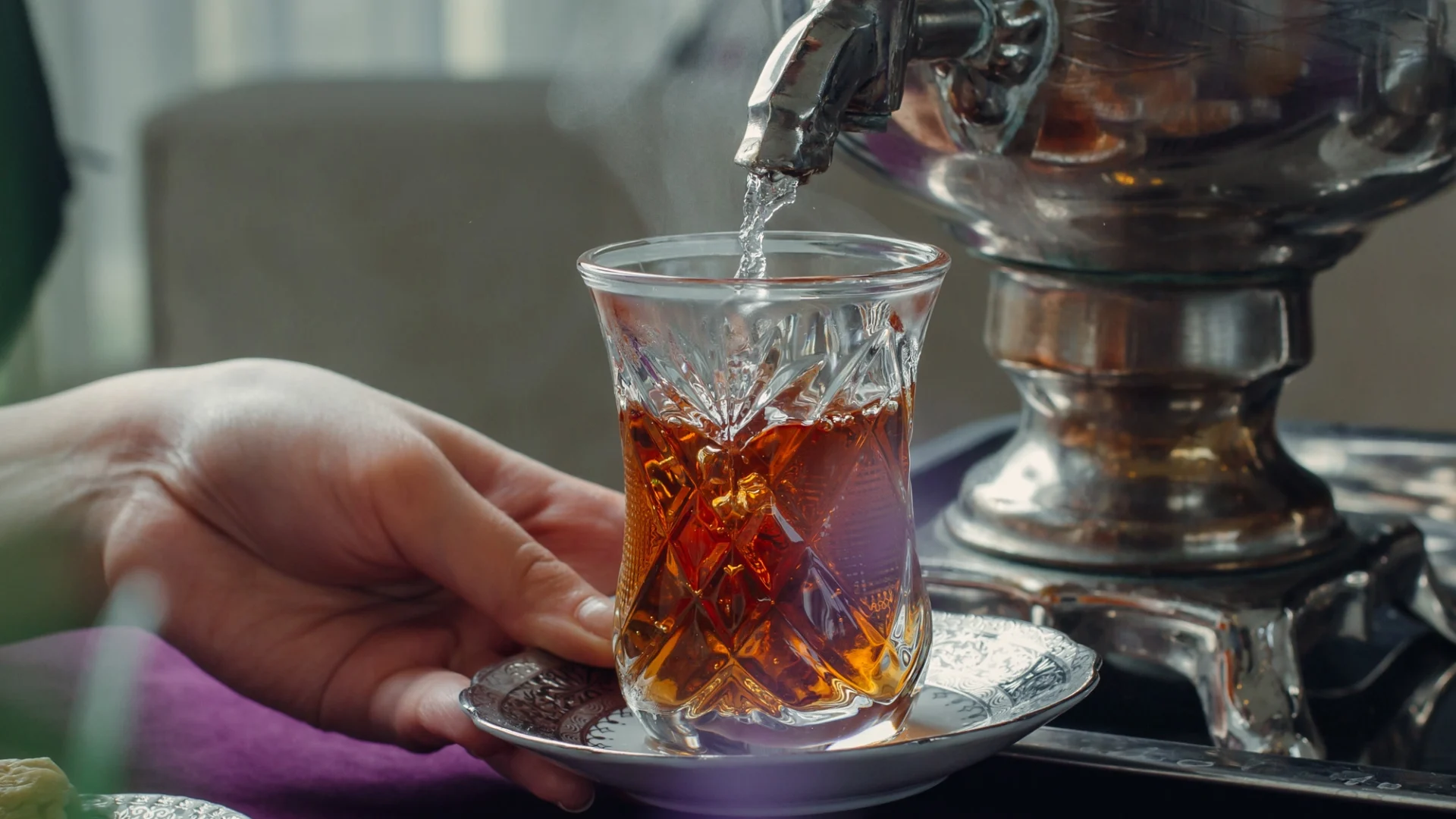 woman-pouring-hot-water-into-glass-with-black-tea-from-samovar